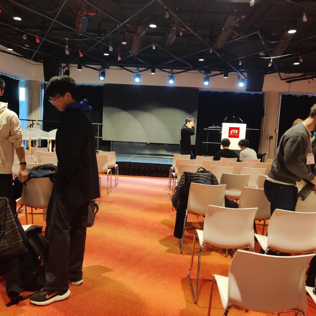 GraphQuon 2024 auditorium at ÉTS — red carpet, white chairs, projection screen and ÉTS podium