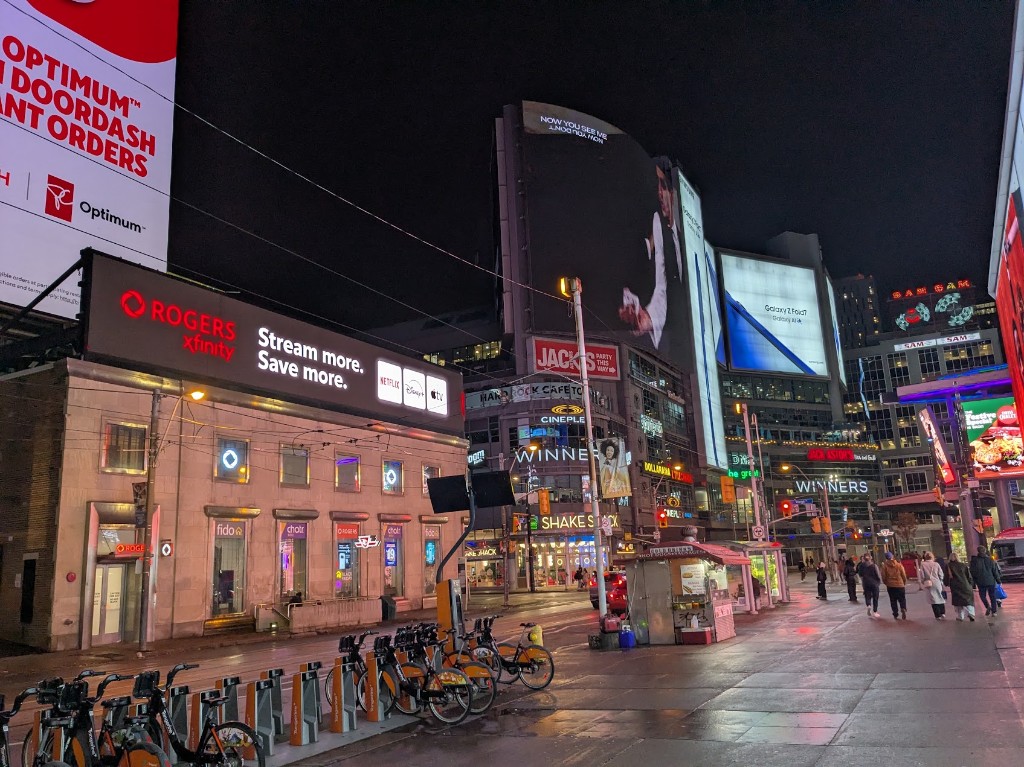 Yonge–Dundas Square at night — digital billboards and wet pavement